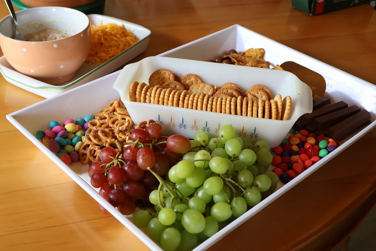 A platter of assorted snacks including grapes, pretzels, and crackers